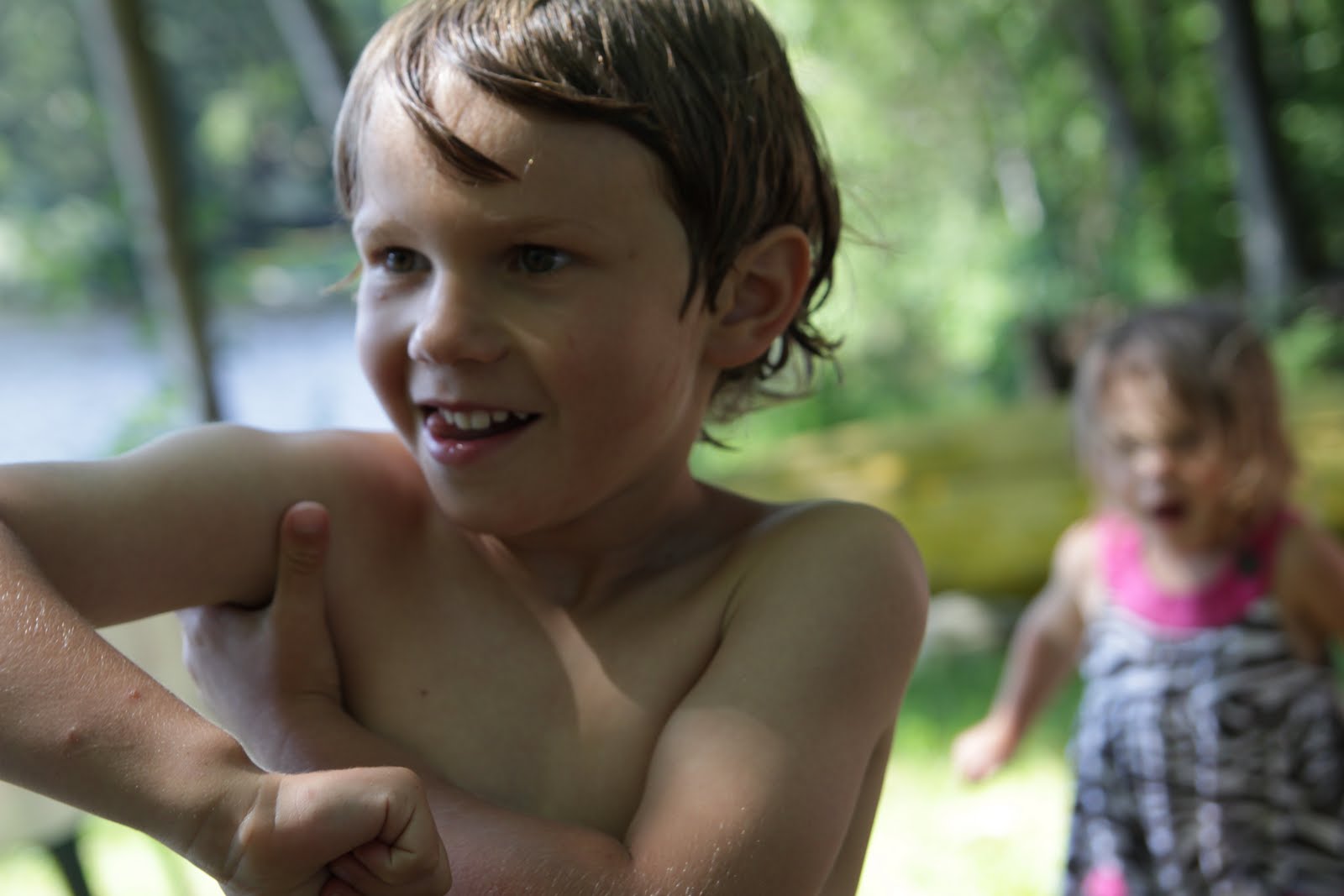A boy armpit farting, with his sister upset in the background.